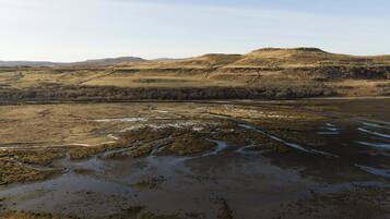Een uitgestrekt landschap met een rivier die door een vallei kronkelt, omgeven door glooiende heuvels.