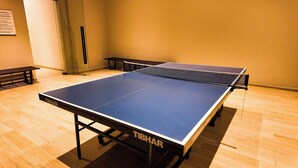 Ein Tischtennis-Tisch mit Netz in einem Raum mit Holzboden und einer Bank.