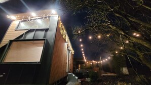 A modern building with a large window and a balcony, surrounded by string lights.