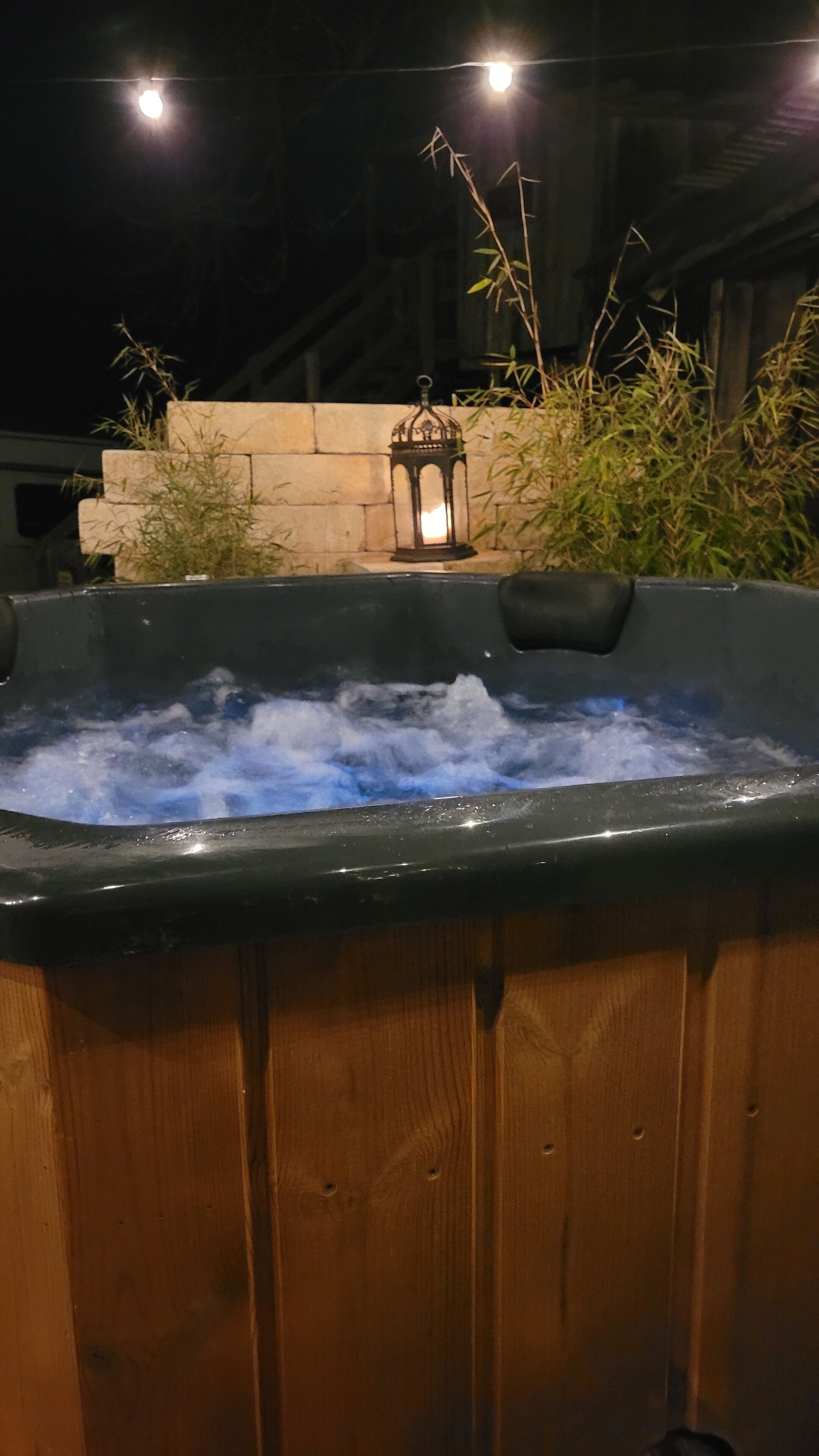 Un bain à remous avec une lanterne et des plantes en bambou en arrière-plan.