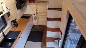 A compact kitchen with wooden walls, a built-in stove, and a window overlooking a cityscape.