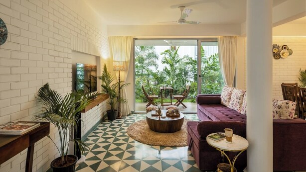 Een moderne woonkamer met een bank, salontafel en potplanten.