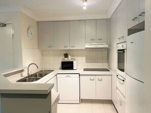A modern kitchen with white cabinetry, a built-in microwave, a dishwasher, and a refrigerator. - 300m to Beach • Surfers Paradise • 3 Beds (Surfers Paradise)