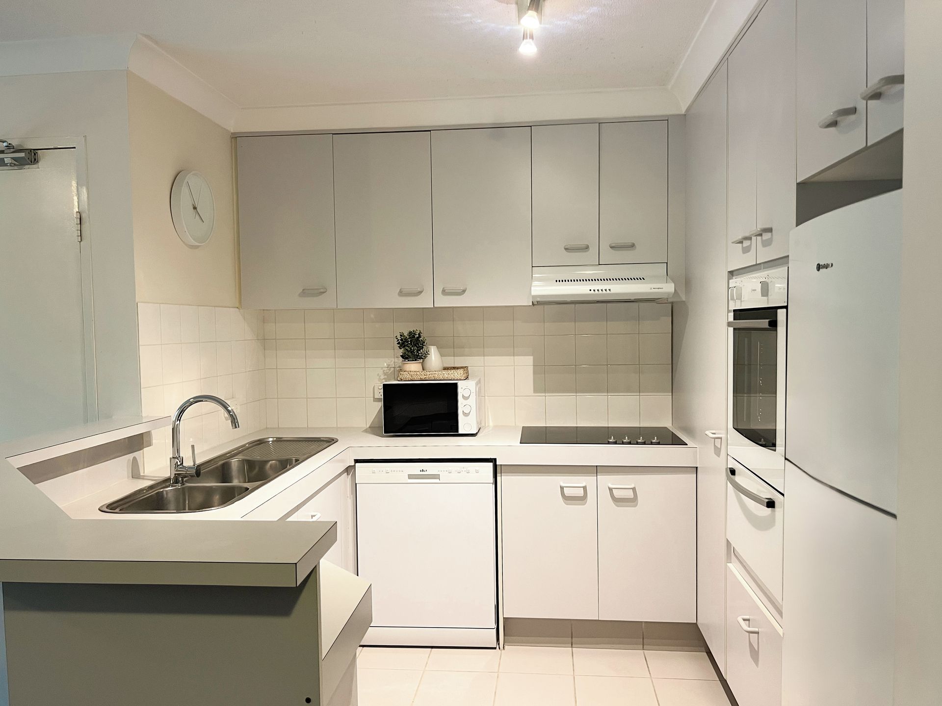 A modern kitchen with white cabinetry, a built-in microwave, a dishwasher, and a refrigerator.