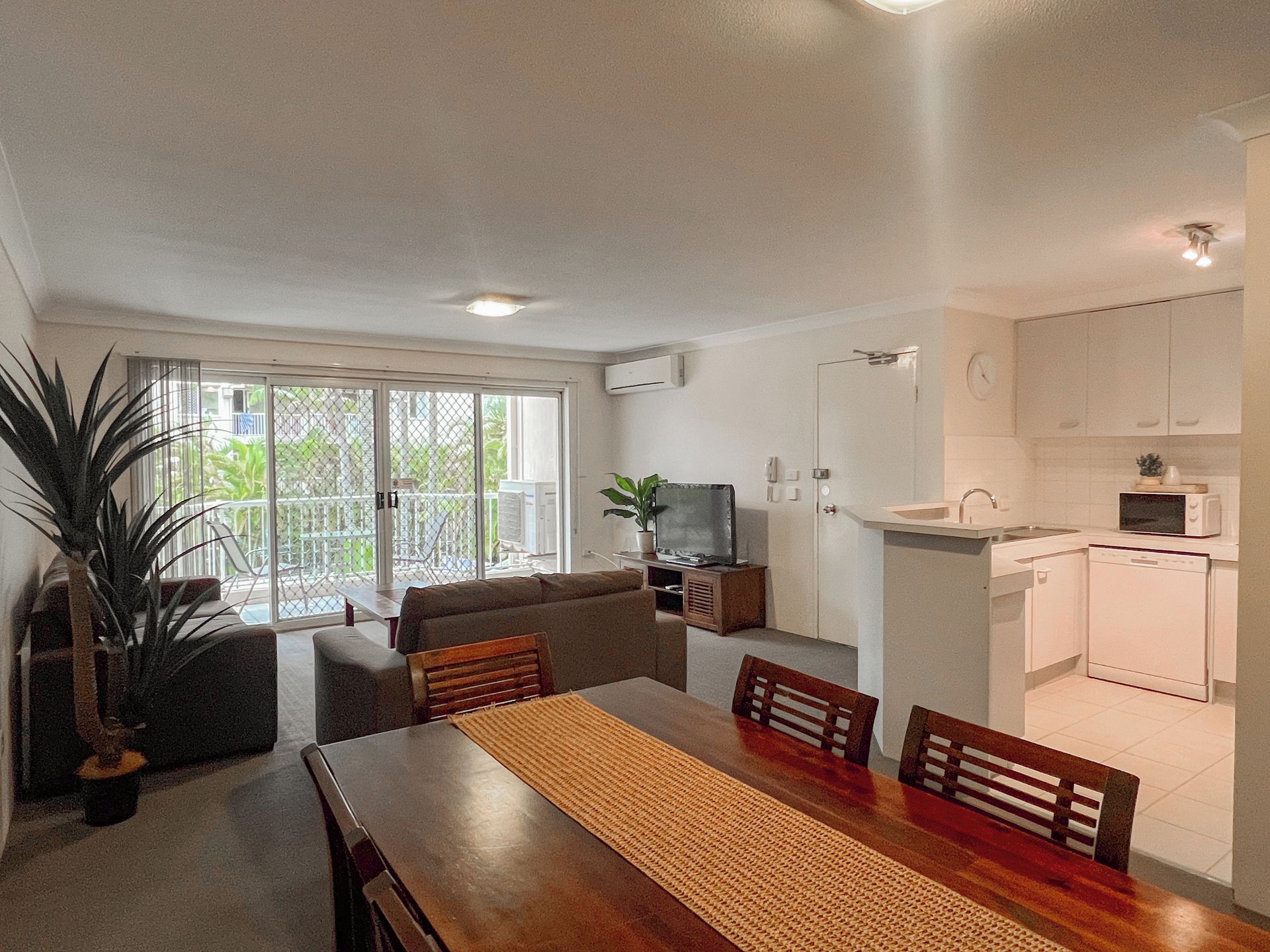 Un espace de vie compact comprenant un coin repas, une kitchenette et une porte-fenêtre coulissante donnant sur un balcon.