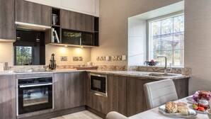 Una cucina moderna con mobili in legno scuro, forno integrato e un'ampia finestra che permette l'ingresso di luce naturale.