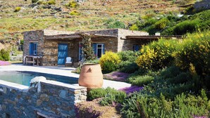 A stone house with a pool, surrounded by lush vegetation and a hillside. - Cycladic Cottage with sea access in a hideaway of rare character (Andros)