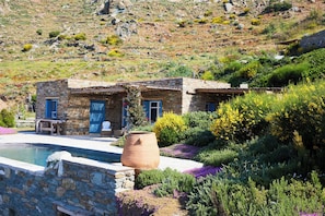 Ein Steinhhaus mit Pool, umgeben von üppiger Vegetation und einer Hanglage.