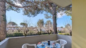 A covered outdoor seating area with a table and chairs, a patterned tablecloth, and a view of trees and houses in the background. - Calm and green residential house (Bibione)