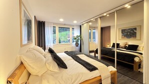 Un dormitorio con una cama grande, una mesita de noche, un espejo y una ventana con cortinas.
