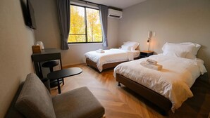 Habitación de hotel con dos camas, un escritorio y una silla.