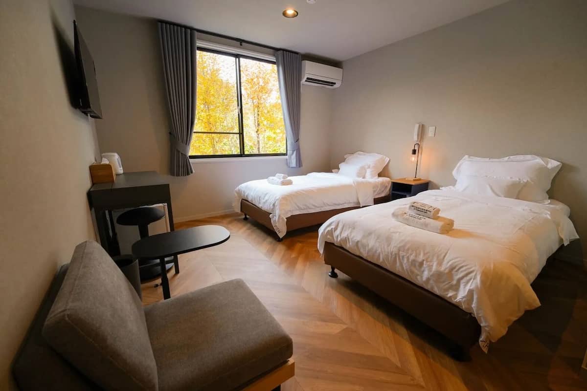 A hotel room with two beds, a desk, and a chair.