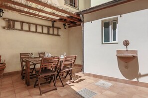 A patio with a wooden table and chairs, a hanging light fixture, and a wall-mounted sink. - Santa Maria Novella Elegant (firenze)