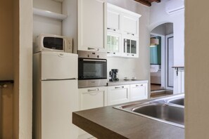A modern kitchen with white cabinetry, a built-in oven, a microwave, and a coffee maker. - Santa Maria Novella Elegant (firenze)