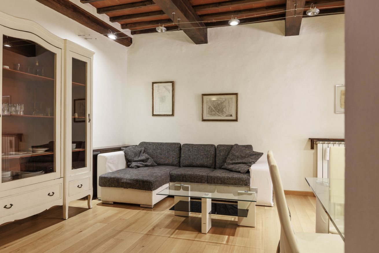 A modern living room with a sectional sofa, a glass coffee table, and a white cabinet with glass doors.