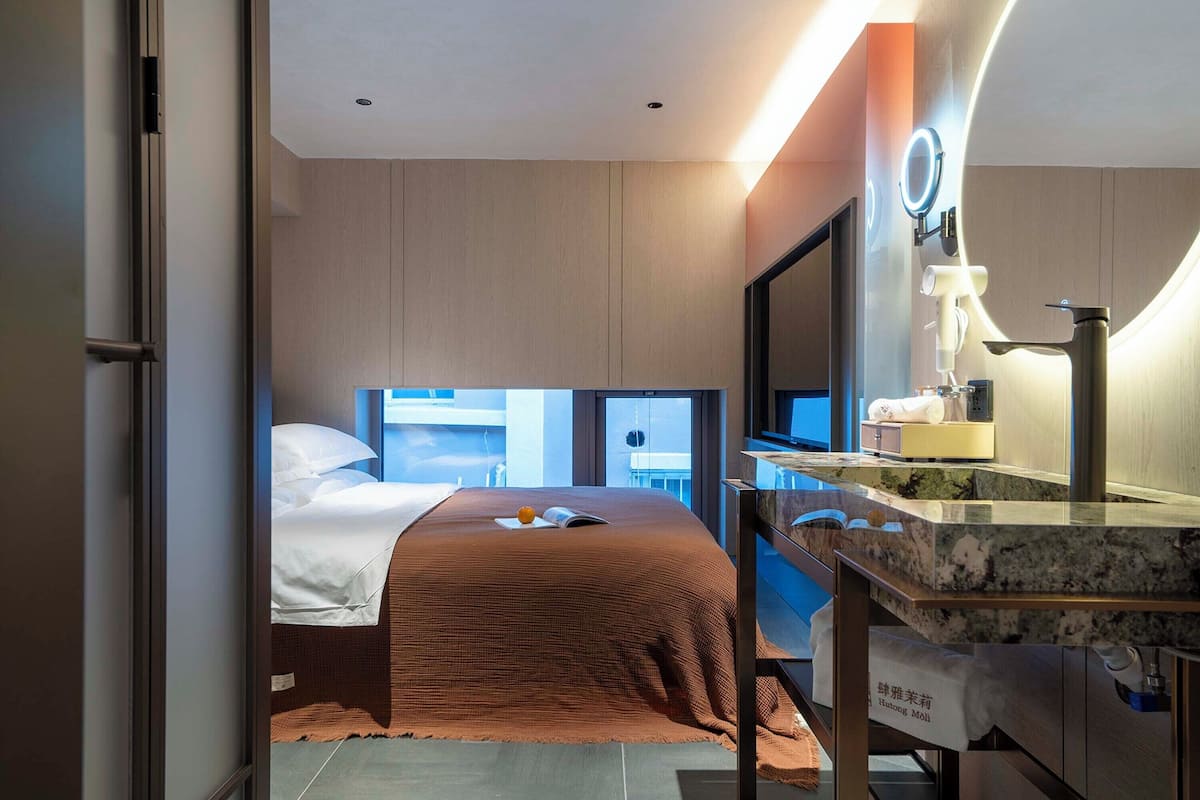 Una habitación de hotel moderna con cama, baño con espejo y vistas a la ciudad.