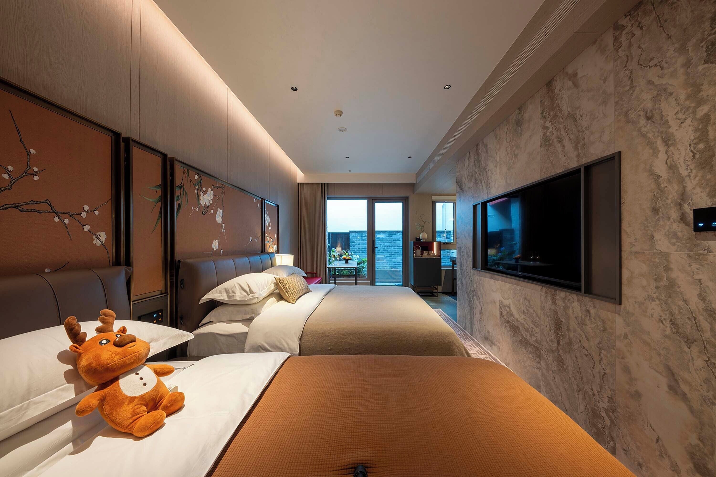 A hotel room with a large bed, a sofa, a TV, and a view of the city.