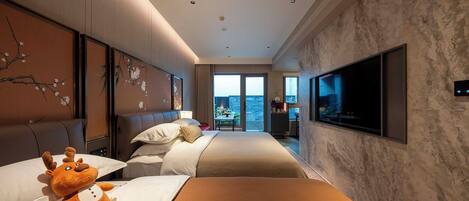 A hotel room with a large bed, a sofa, a TV, and a view of the city.