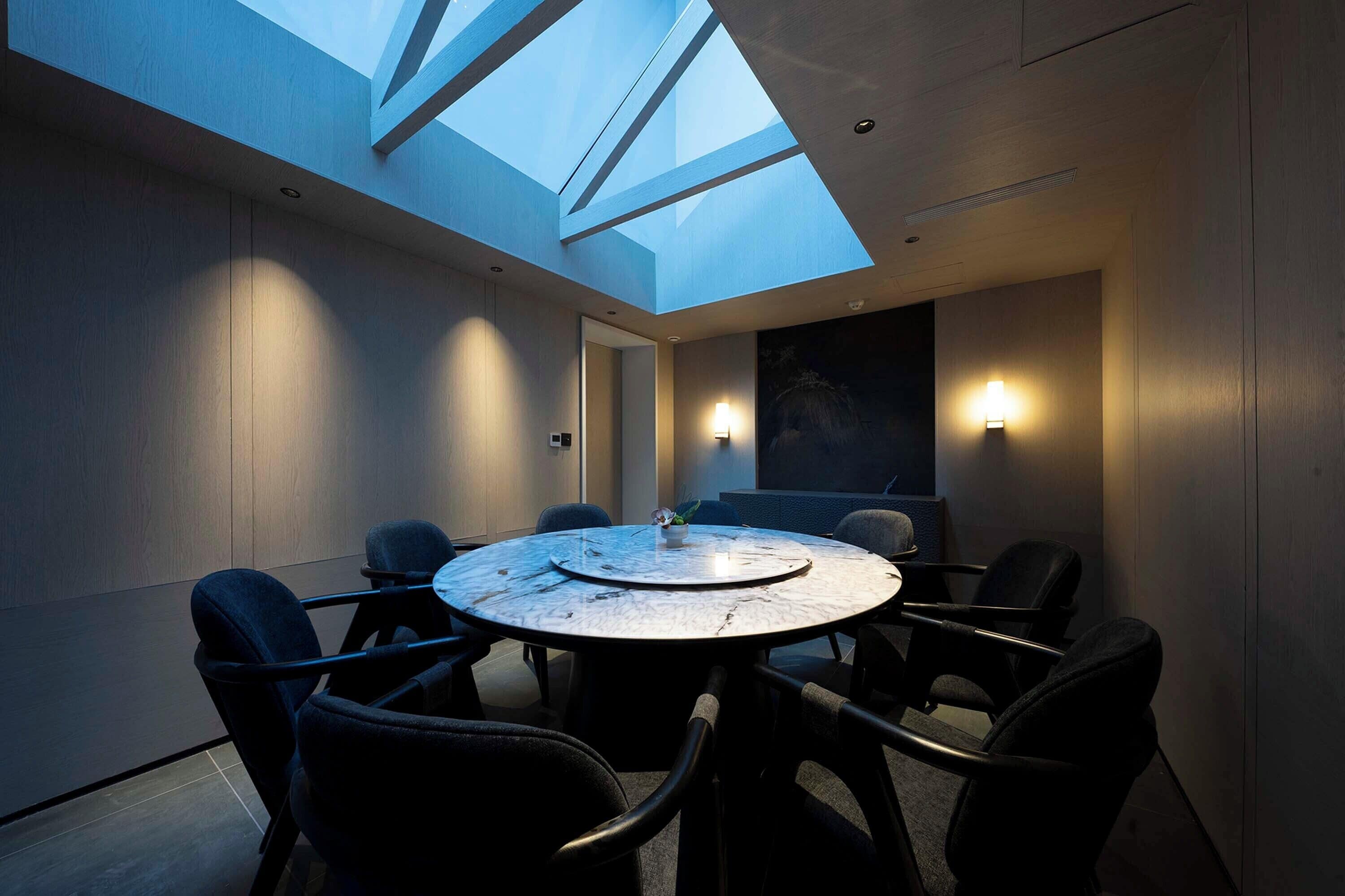A conference room with a skylight, round table, and chairs.