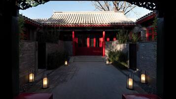 Puerta tradicional china que da a un edificio con techo de tejas y detalles en rojo.