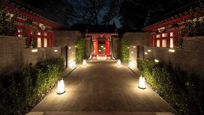 A traditional building with a tiled roof, a central entrance with a red gate, and a brick pathway leading to it. - Hutong Mòlì Hotel (Beijing)