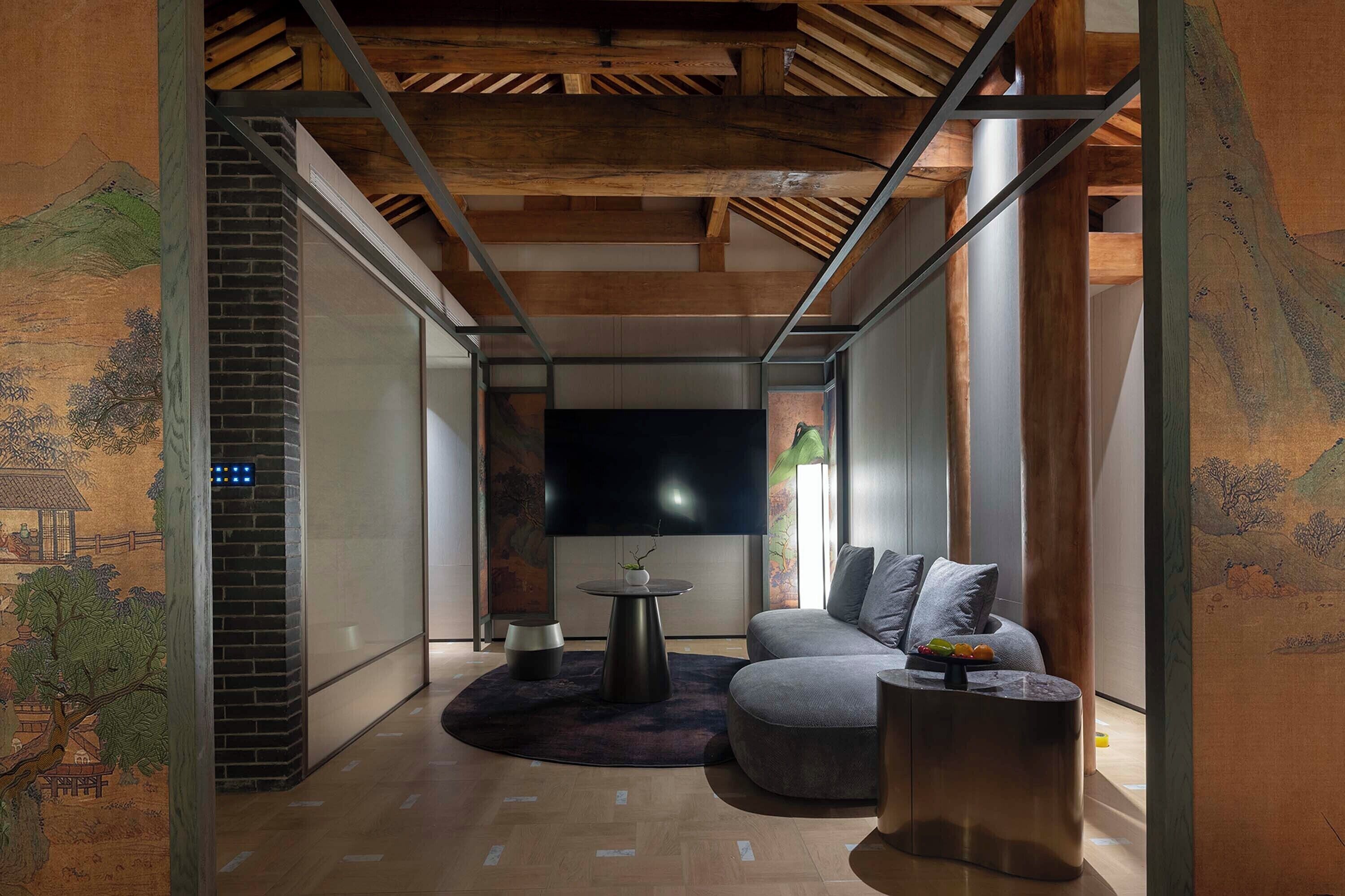 A modern living room with a large flat-screen TV, a round coffee table, a sofa, and a fireplace.