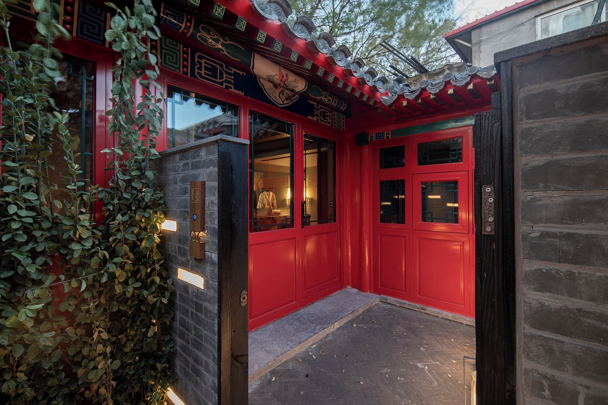 A traditional building with red doors and windows, a tiled roof, and a brick wall.