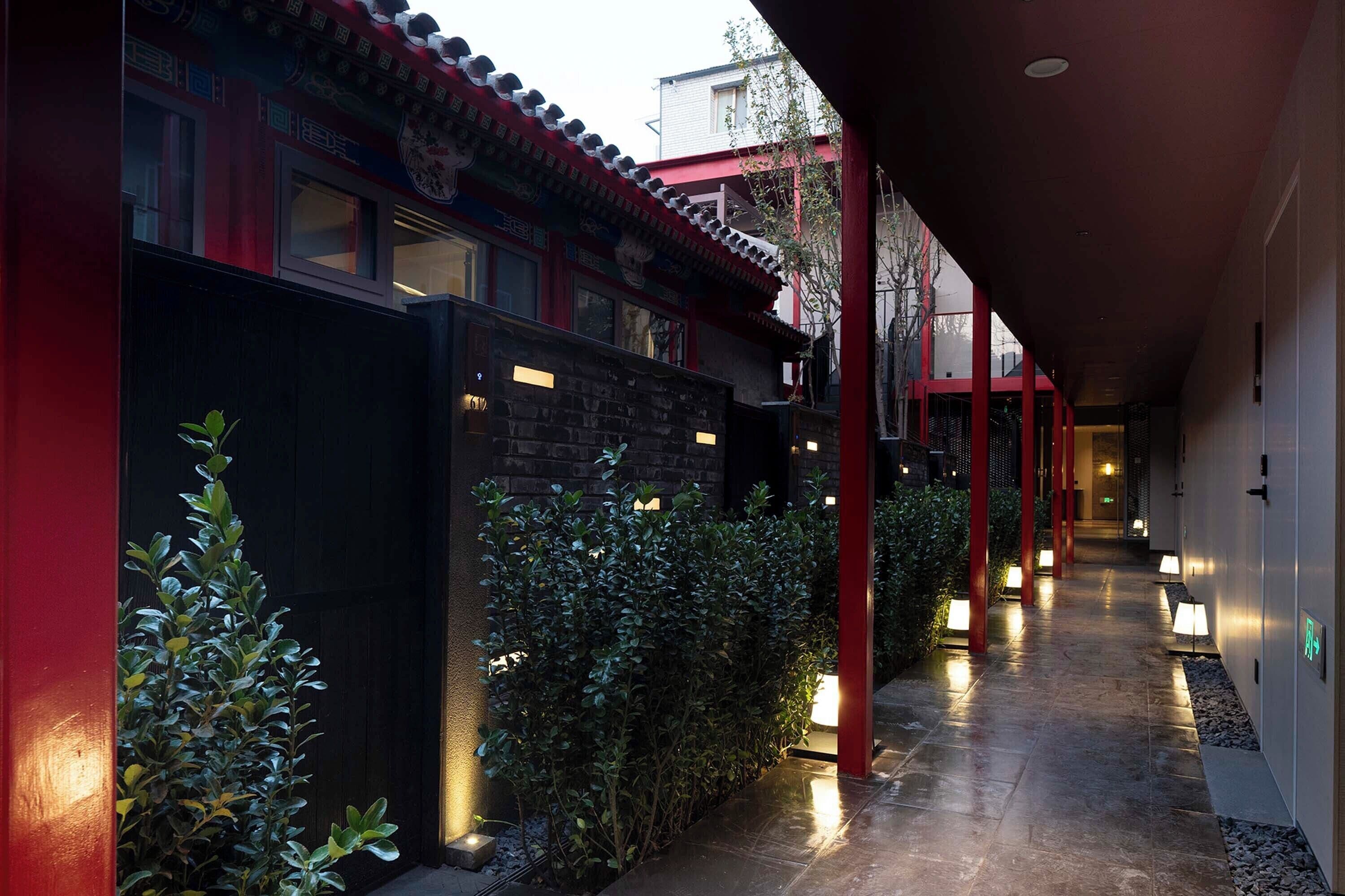 A corridor with traditional architecture, including red pillars and a tiled floor.
