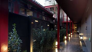 A corridor with traditional architecture, including red pillars and a tiled floor.