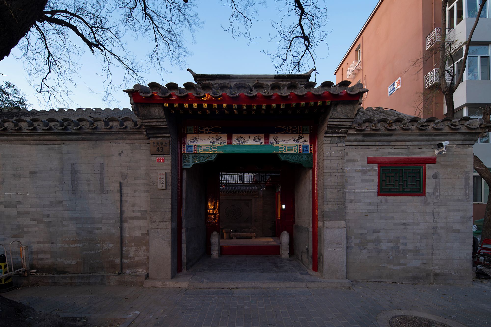 Una puerta tradicional china con diseños intrincados y un tejado rojo, que da paso a un patio.