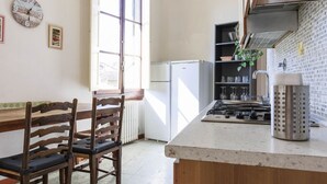 A kitchen with a wooden dining table, chairs, a refrigerator, a stove, and a window. - Faenza Huge Apartment (Firenze)