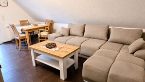 Una sala de estar con un sofá, una mesa de centro de madera y un comedor con sillas y una mesa.