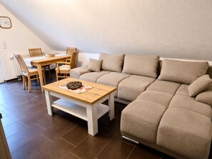A living room with a sofa, a wooden coffee table, and a dining area with chairs and a table.