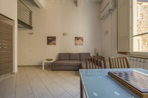 Ein modernes Wohnzimmer mit Glastisch, einer Couch und einem kleinen Beistelltisch.
