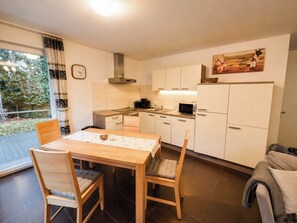 Uma cozinha compacta com área de jantar, um relógio e um quadro na parede.