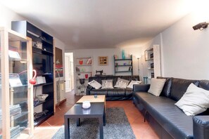 A living room with a black leather sofa, a coffee table, and a bookshelf. - Carmine Comfort Apartment (Firenze)