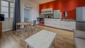 Una cocina moderna con gabinetes blancos, una pared de acento roja y un refrigerador de acero inoxidable.