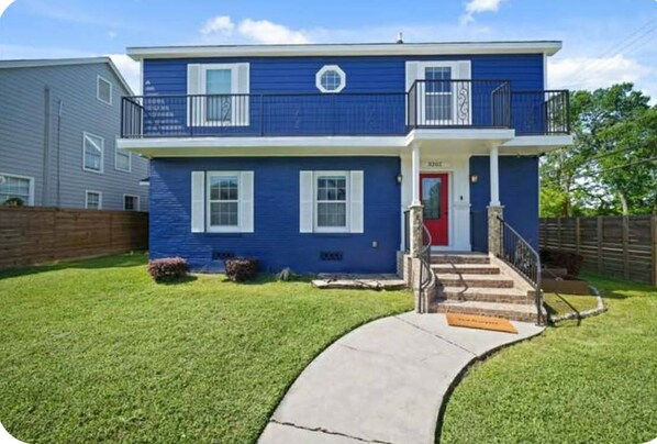 A two-story house with a red door, a balcony on the second floor, and a well-maintained lawn. - Lucky House 2 Tranquility in the Middle of Houston (Houston)