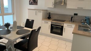 A modern kitchen with a dining area, featuring a stove, oven, and various appliances. - Feel good for 1-4 people at Casa Berg in Spiesen-Elversberg (Spiesen-Elversberg)