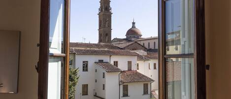 A view from an open window of a building with a bell tower and a dome, suggesting a historical or religious building.