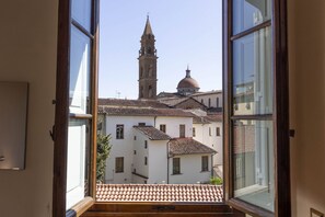 A view from an open window of a building with a bell tower and a dome, suggesting a historical or religious building. - Santo Spirito Huge Apartment (Florence)