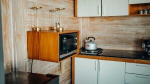Una cocina compacta con armarios de madera, un microondas integrado y una tetera sobre la estufa.