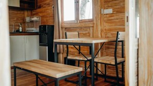 Un interior de madera con cocina, una mesa de comedor con sillas y una ventana con vista a una palmera.