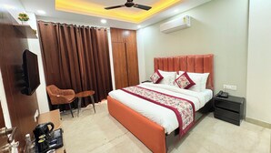 A modern bedroom with a bed, a desk, a chair, a ceiling fan, and an air conditioning unit. - The Nuvon Residency CR Park  (New Delhi)