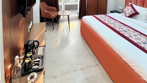 A modern hotel room with a bed, a desk, a chair, a TV, and a ceiling fan. - The Nuvon Residency CR Park  (New Delhi)