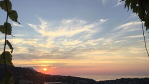 Um pôr do sol sobre uma cidade costeira, com edifícios e barcos.