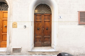A double wooden door with a small step leading up to it, a number '9' sign above, and a small vent below. - Santo Spirito Living (Firenze)