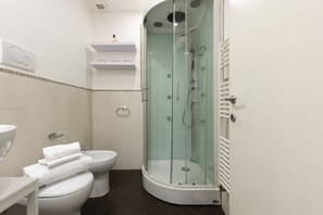 A modern bathroom with a glass-enclosed shower, a toilet, and a sink. - Santo Spirito Living (Firenze)