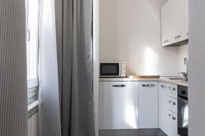 A compact kitchen with white cabinets, a microwave, and a sink. - Santo Spirito Living (Firenze)