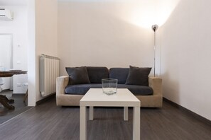 A modern living room with a beige sofa, a white coffee table, and a floor lamp. - Santo Spirito Living (Firenze)